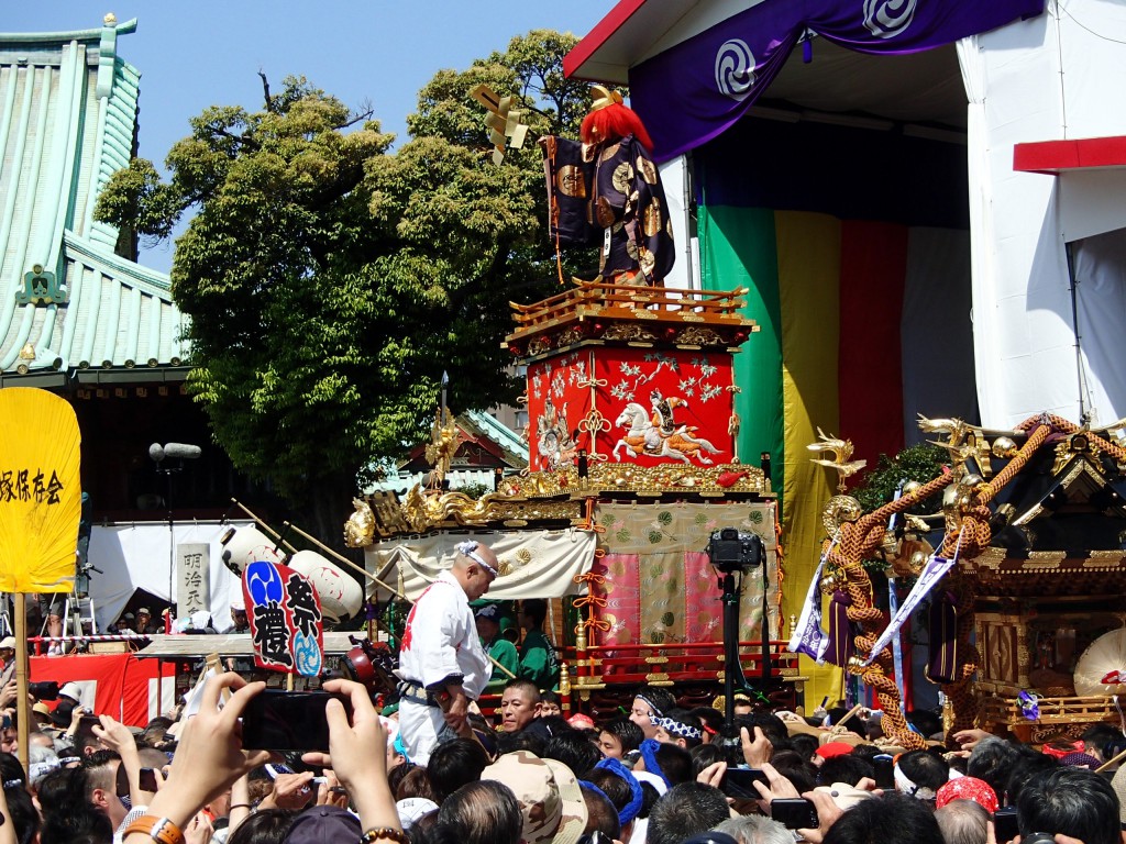 神輿がおっきくて門をくぐれないので、横から廻って境内に到着。江戸型山車の人形がうしろに飾られているけど人が多すぎてこれ以上近づくこともできない。